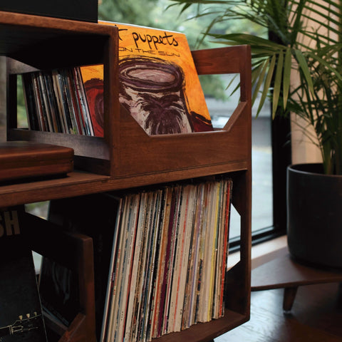 A close up of the forward facing flip bins displaying the art of a vinyl record in the irving vinyl record storage and turntable stand furnture